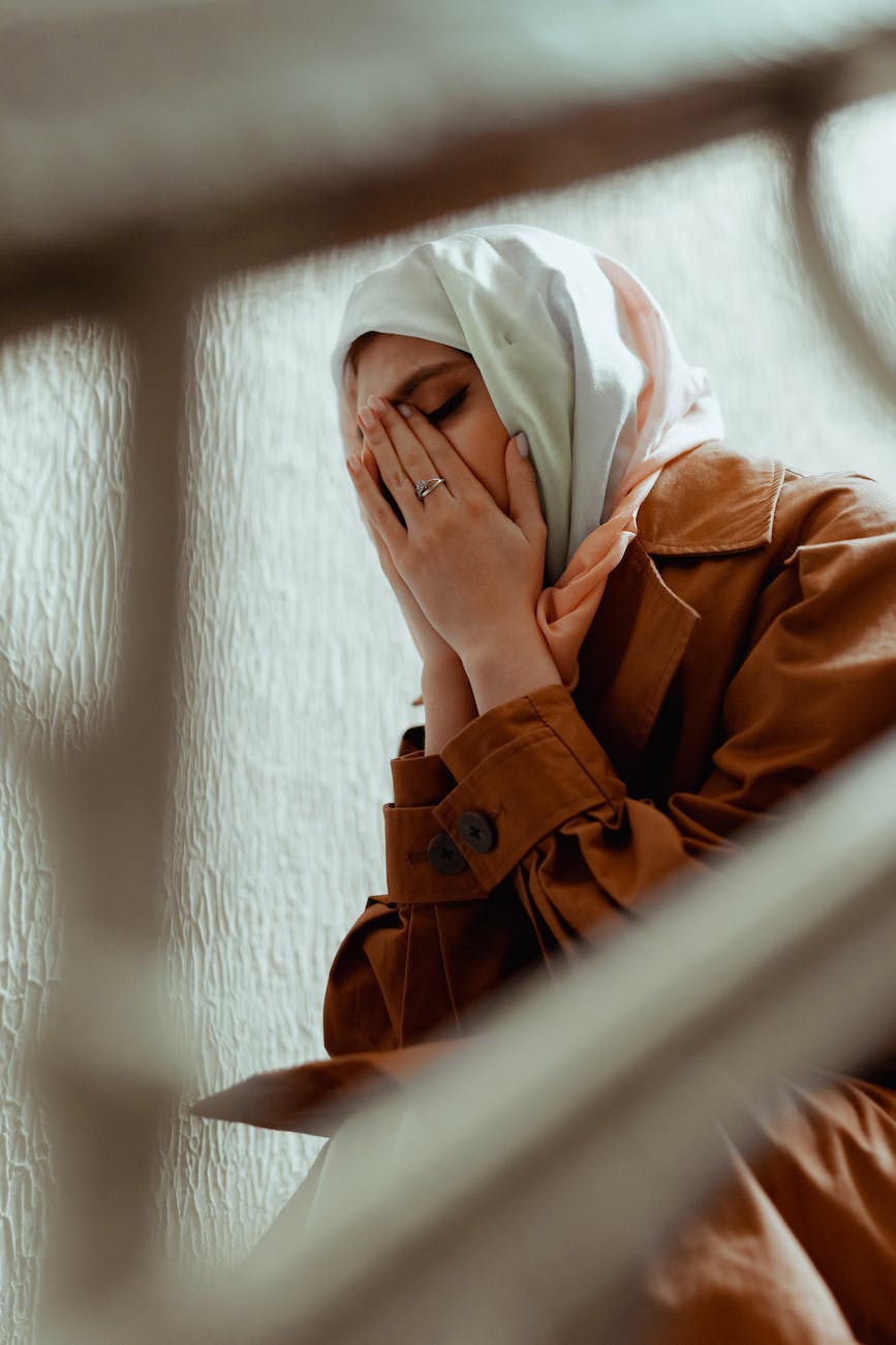 a crying woman in a hijab and a brown coat